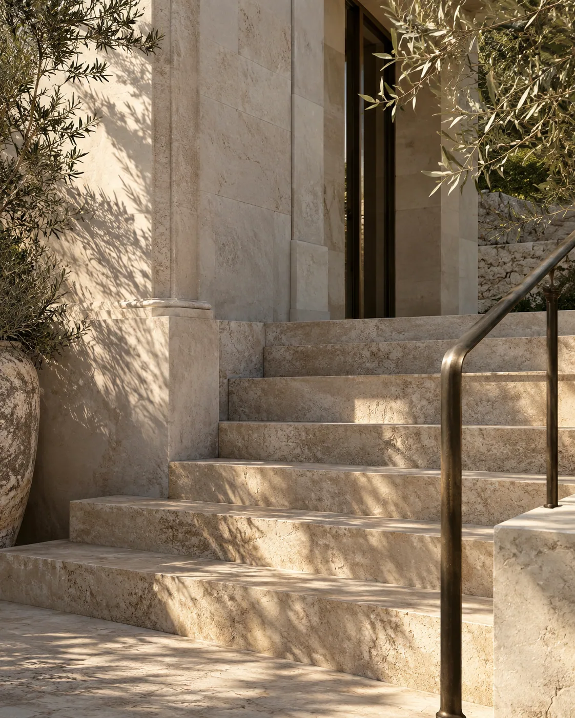 Illustrative hand-finished limestone stairs with a bronze railing and soft sunlight.
